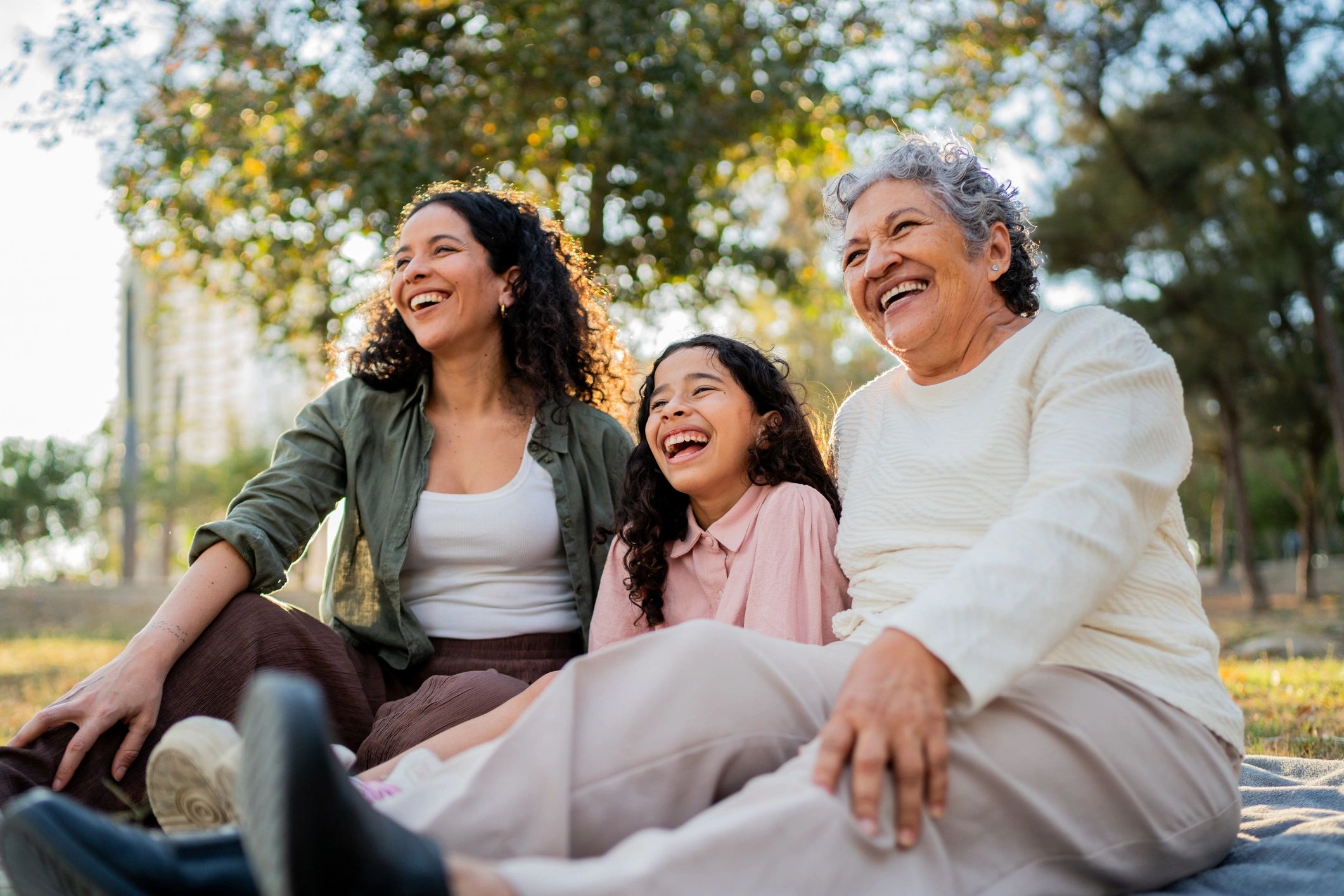 Three generations of women laughing together outdoors